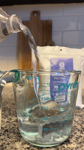 Pouring water into a Pyrex measuring cup for butterfly pea flower tea caffeine free preparation