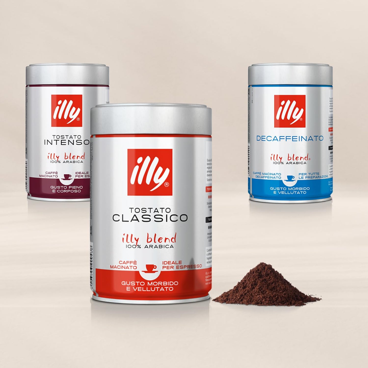 Illy ground espresso coffee tins in Classico, Intenso and Decaffeinato blends with a pile of ground coffee