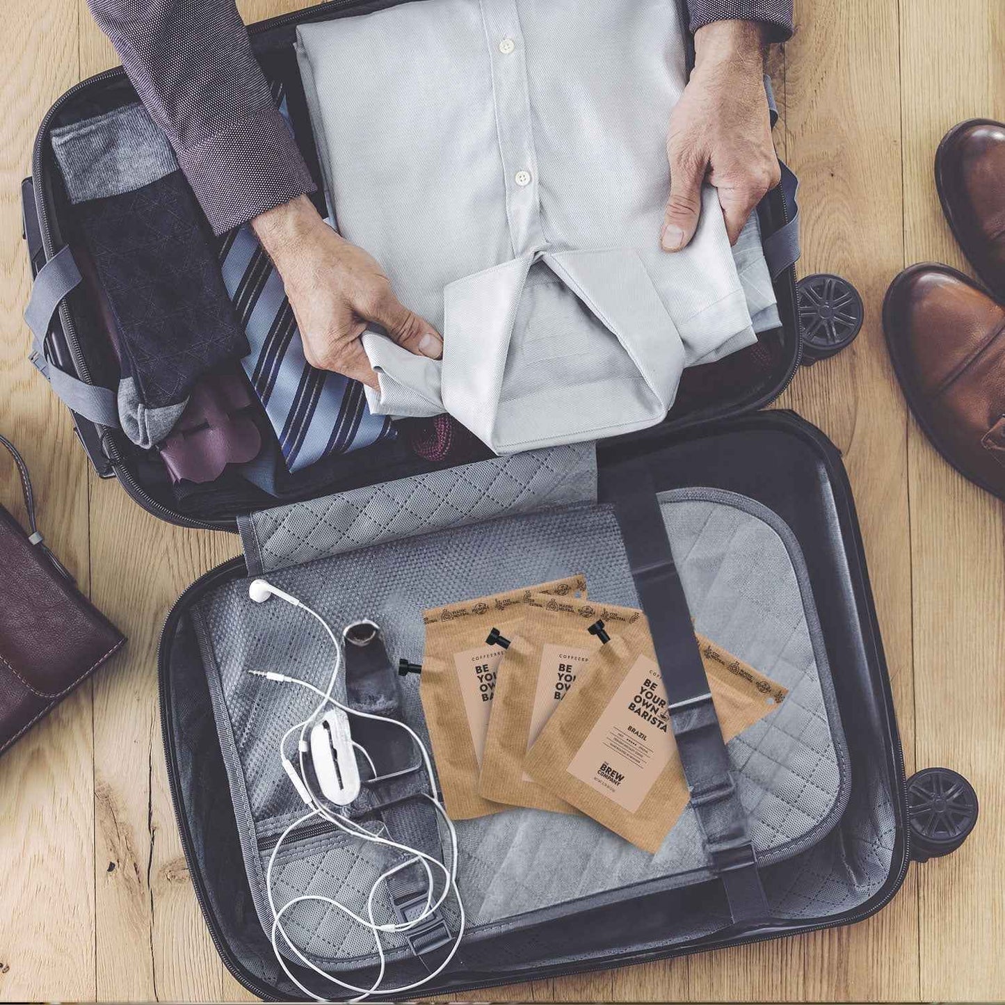 The Brew Company 25 piece coffee taster set included in an open travel suitcase with clothes and accessories