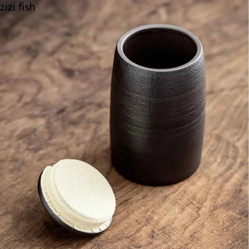 Black sealed tea storage jar with textured surface and removable lid on wooden table