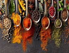 Gourmet spices from around the world displayed in spoons with vibrant colors and textures on dark surface