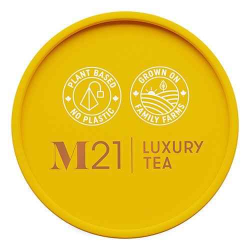 Yellow lid of DC-Tega Tea container labeled M21 luxury tea with plant based and family farm icons for maple luxury herbal tea