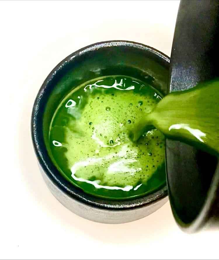 Pouring vibrant green organic matcha powder 40g herbal tea by DC-Tega Tea into a black cup